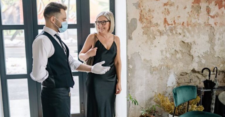 Customer Satisfaction - Waiter in a Luxury Hotel Inviting a Customer to Take a Seat