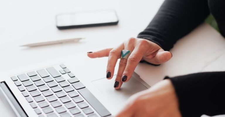 Startup Challenges - Crop female using touchpad on laptop in office