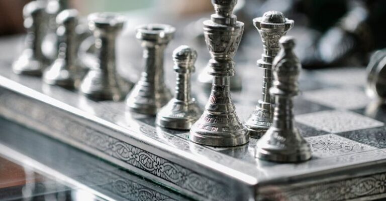 Competitive Markets - Classic metal chess board with set figurines designed with carved ornaments and placed on glass table in light room