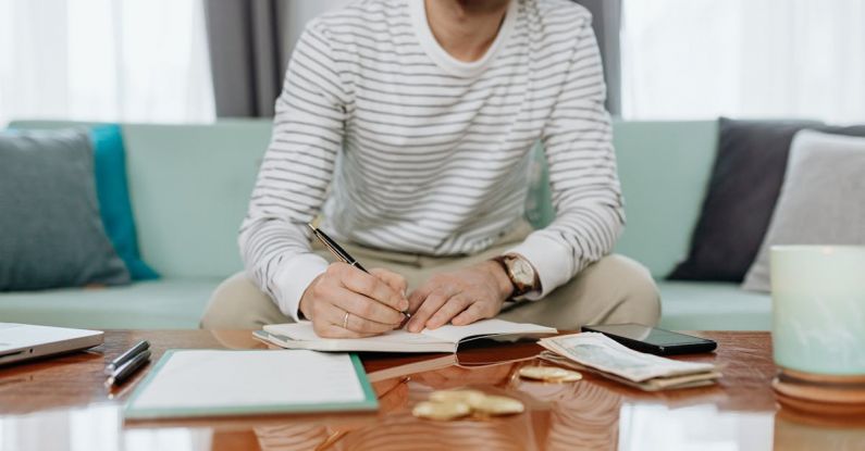 Business Budgeting - Man in White and Gray Striped Long Sleeve Shirt Sitting at the Table