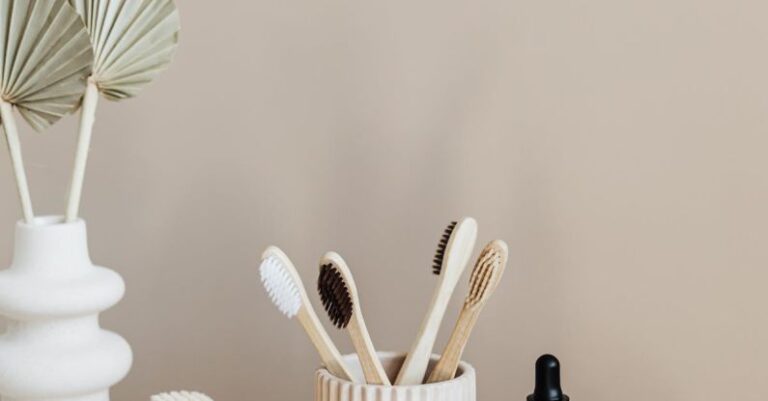 Sustainable Investing - Collection of bamboo toothbrushes and organic natural soaps with wooden body brush arranged with recyclable glass bottle with natural oil and ceramic vase with artificial plant