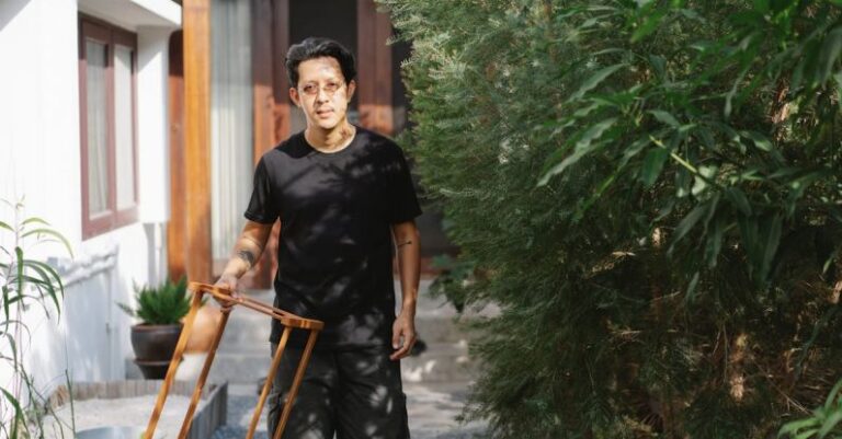 Just-In-Time Production - Young Asian man in casual clothes walking in garden with wooden frames and looking at camera